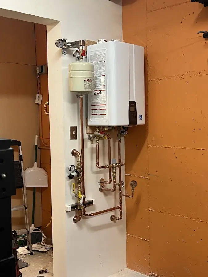 Plumbing technician inspecting water heater connections in London Grove